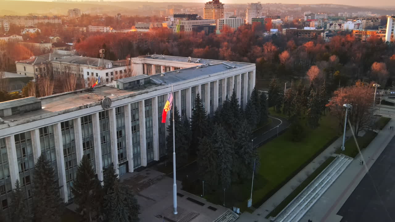 Aerial drone view of Government House at sunset. Building with flag and road in front of it, bare trees in Chisinau, Moldova