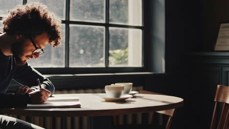 man writing in a cafe