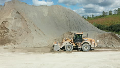 side view of front loader pushing limestone to form large pile in quarry