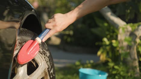 Still-shot-of-a-hand-washing-the-tire-and-rim-of-the-car-with-a-brush