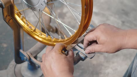 technician man working motorcycle wheel has spokes weave up on mechanic tool new steel wheel