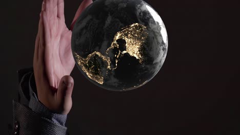 vertical of planet earth world globe illuminated at night rotate above palm hand , creation gods religion robot artificial intelligence concept