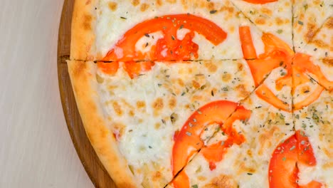 la mitad de cortar pizza con tomates y queso en una tabla de madera. vista superior.