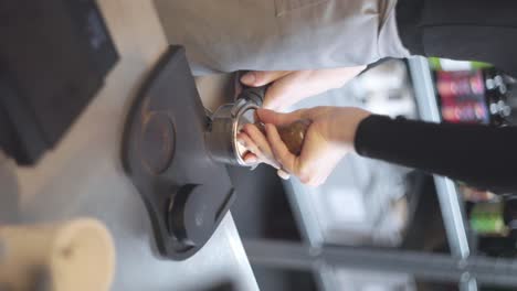 vertical, el barista demuestra cómo preparar el portafiltro de la canasta para la prensa de espresso