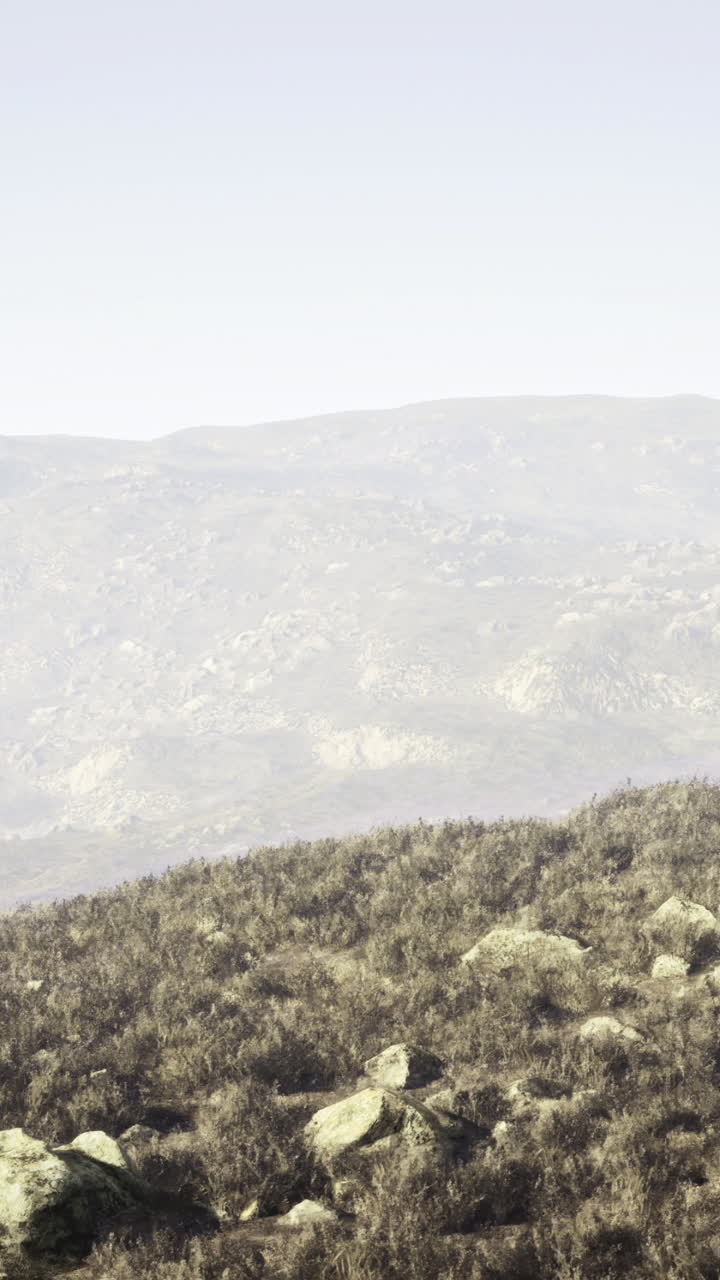 Vast dry landscape with rocky terrain and distant mountains during daytime