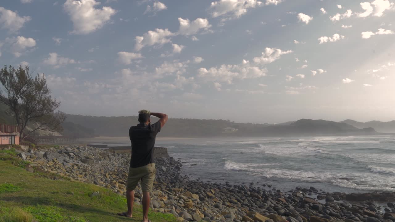 Man gazing at the ocean from a rocky coast