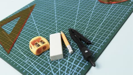 compass, pencil, sharpener, eraser and rulers with pad on white background, in slow motion