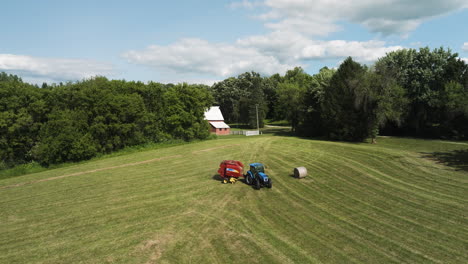 Harvest-farming-scene,-tractor-with-a-trailed-bale-machine-collecting-straw