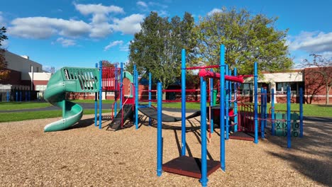 colorful playground with slides and climbing frames on a sunny day, with school in the background in usa