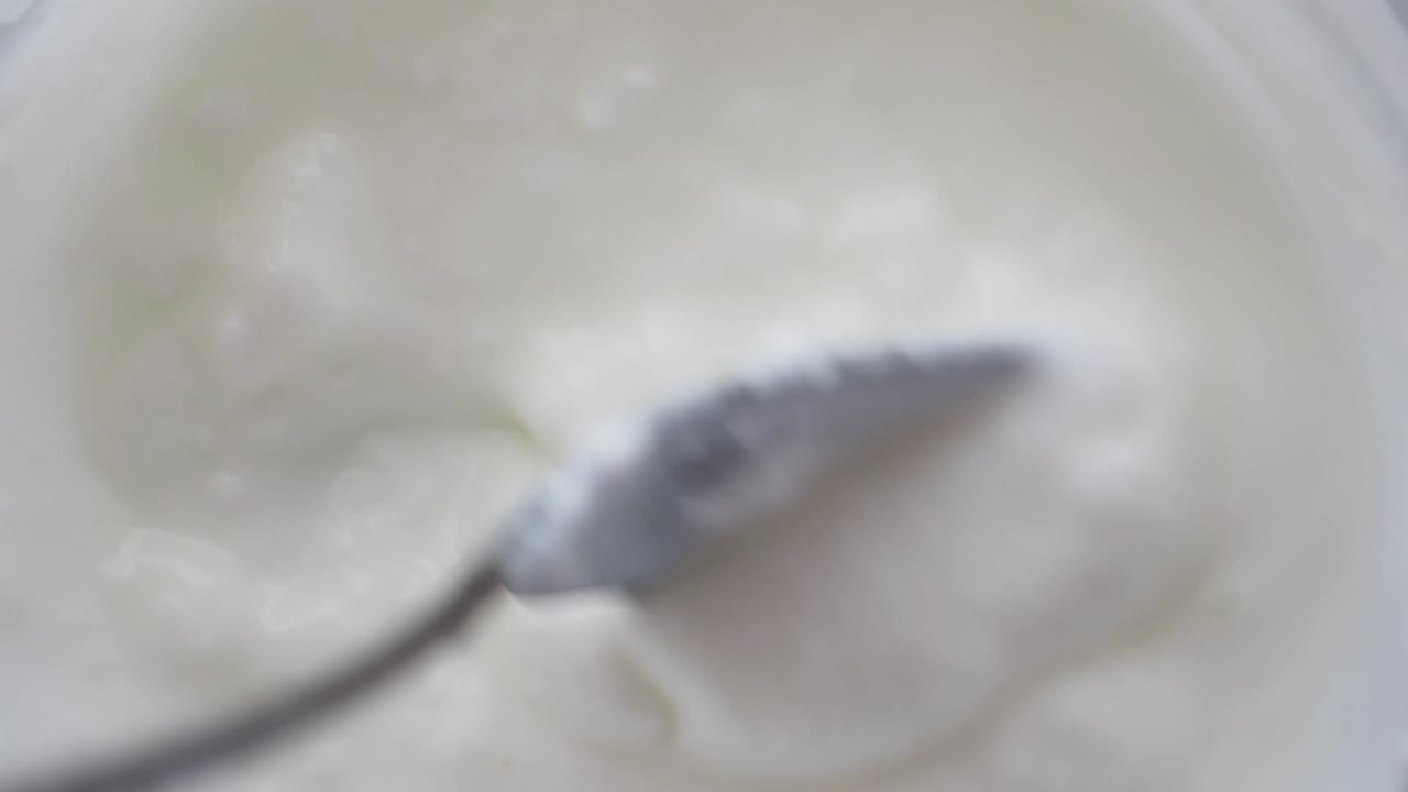 Stirring creamy white yogurt with a spoon