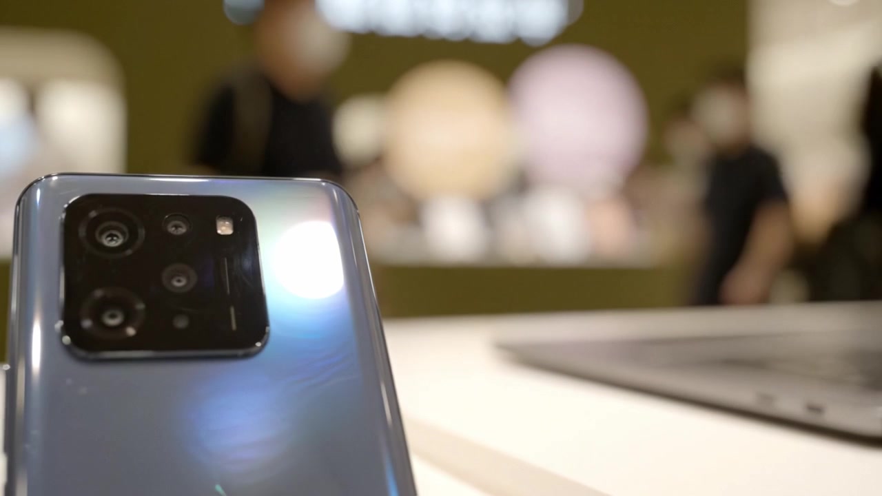 Vetrina di tecnologia moderna con dispositivi e un ambiente di vendita al dettaglio coinvolgente, con branding discreto e focus sui gadget, in mezzo a una vivace interazione con i clienti.