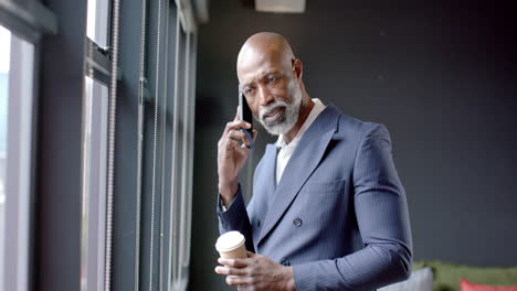 african american businessman talking on smartphone in office with copy space