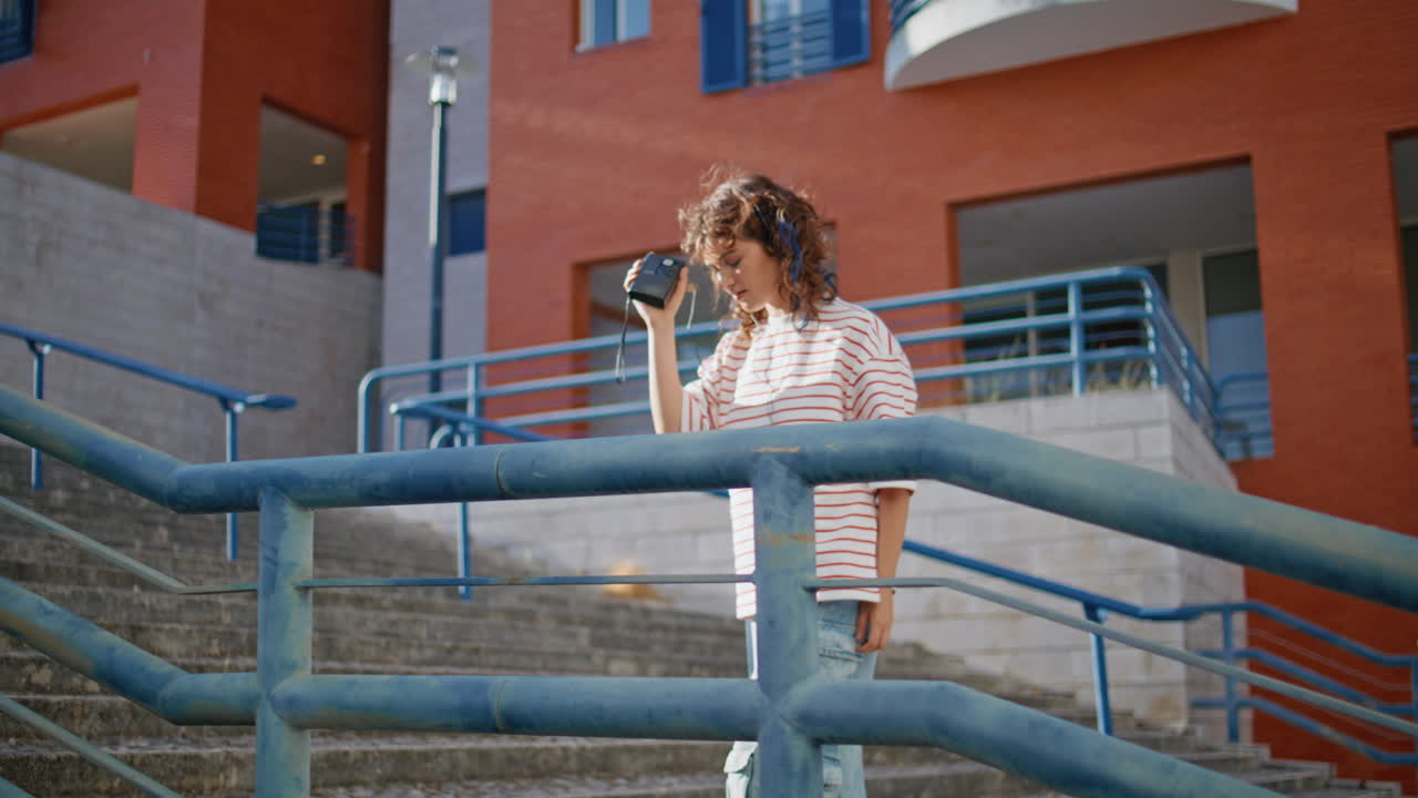 auriculares chica bailando a la luz del sol sosteniendo un reproductor portátil de cassette al aire libre.