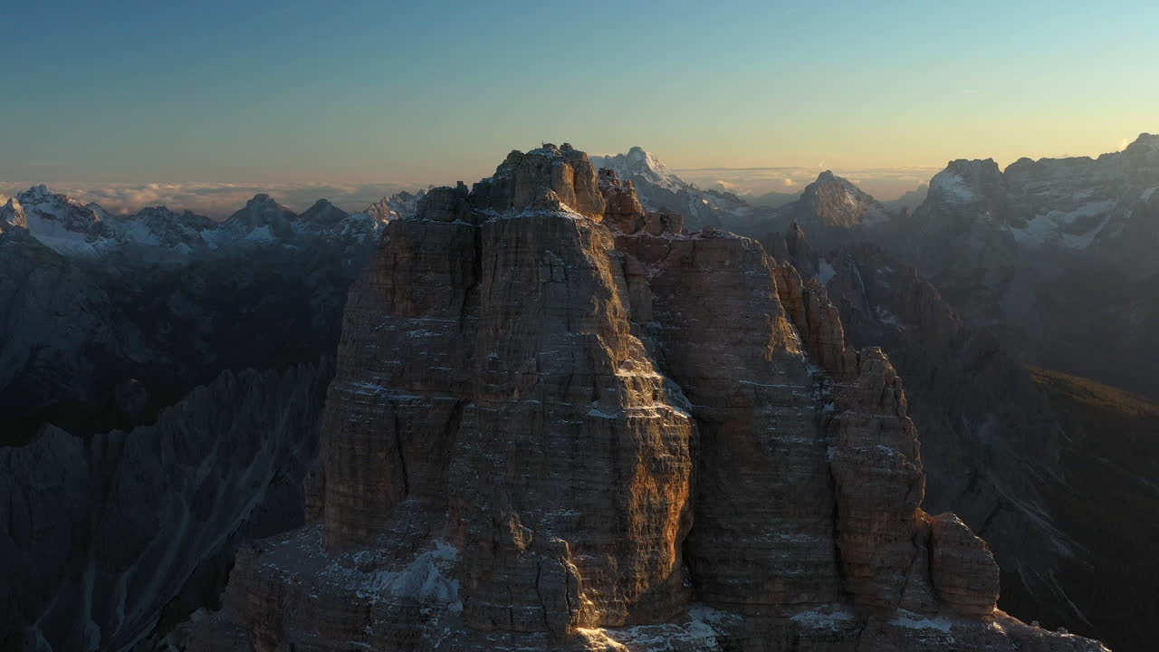 drone cinematografico rotante girato di tre cime di lavaredo in italia, centrato su un picco roccioso con montagne selvagge tutt'intorno