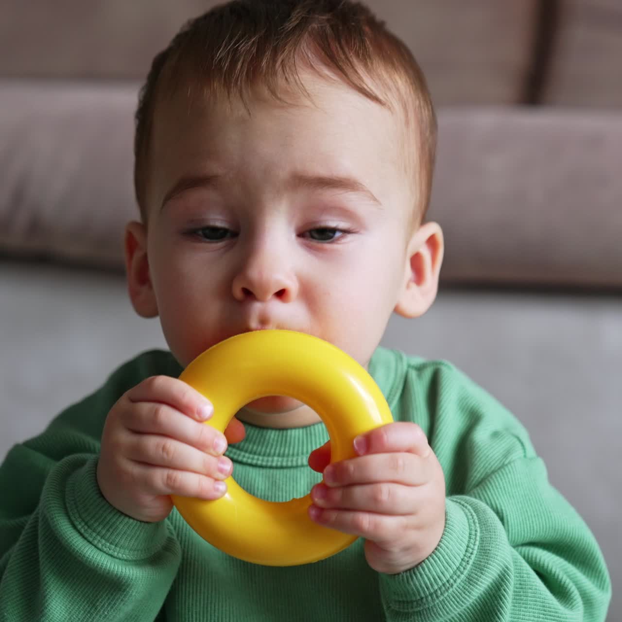 Funny cute kid tasting his plastic toys. Portrait of an adorable baby playing at home with toys. Close up. Blurred backdrop
