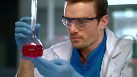 Chemist-in-lab.-Close-up-of-male-chemist-looking-at-liquid-in-glass-flask