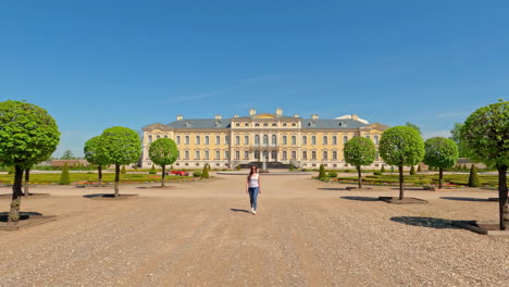 Young-woman-walking-towards-with-Rundale-castle-in-Riga-Latvia-in-summer-day