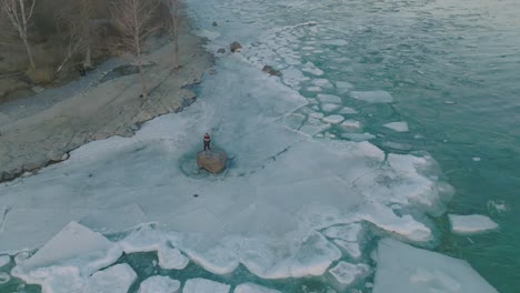 mujeres jóvenes con chaqueta de colores de orgullo en una roca en medio de un lago congelado
