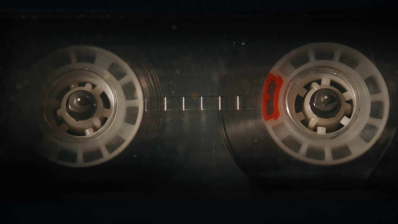 Closeup old cassette playing analog audio in stereo recorder. Macro tape reels