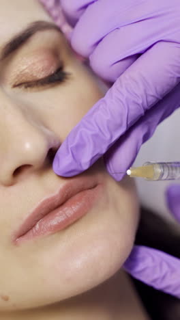 An aesthetic medicine doctor makes Botox to the client's lips. Beauty injections. Cosmetology. Close-up. Vertical video