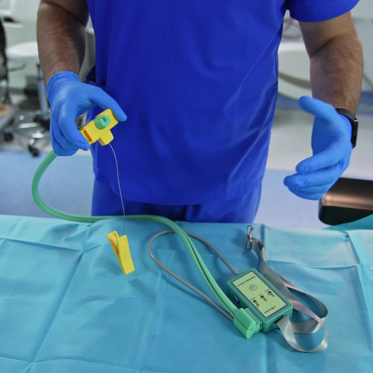 Unrecognized anesthesiologist in latex gloves stands at empty operational table with a device lying on it. Doctor explains the work and exploitation of equipment