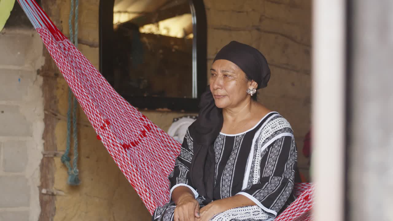An old Latina woman watches a tube television in her simple home
