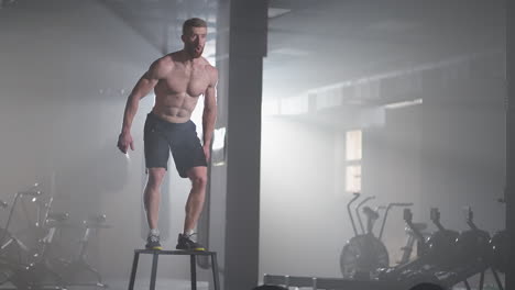 athlete gave exercise. jumping on the box. strong male athlete jumping on cube closeup. tracking shot of fit sportswoman jumping on cube during intense crossfit workout in gym