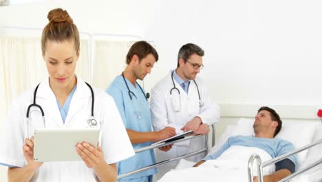 Médicos-Hablando-Con-Un-Paciente-Enfermo-En-La-Cama-Mientras-Uno-Revisa-La-Tableta