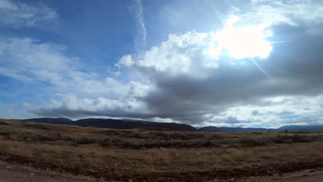 Driving-through-the-Mojave-Desert's-mountain-terrain-on-a-sunny-day---passenger-window-point-of-view