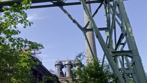 old abandoned industrial plant, rusty metal struts between bushes and nature overgrown landscape park diusburg north in germany overgrown by nature