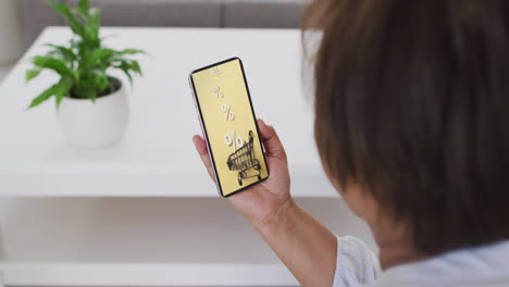 mujer biracial usando teléfono inteligente en casa para comprar en línea, cámara lenta