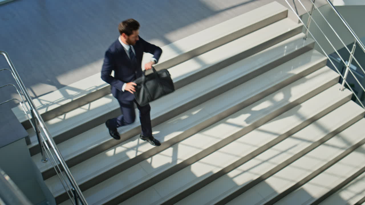 Successful worker hurrying downstairs looking wristwatch. Motivated businessman