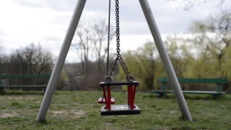 pair of empty swing moving in a lonely outdoor park during quarantine cause of pandemic emergency alert virus