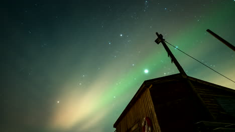 ethereal nightlapse of aurora borealis in sky over skogsfjorden boat house
