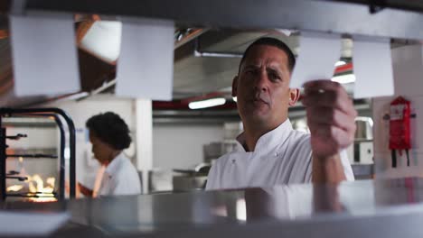 Caucasian-male-chef-taking-orders-and-talking-in-restaurant-kitchen