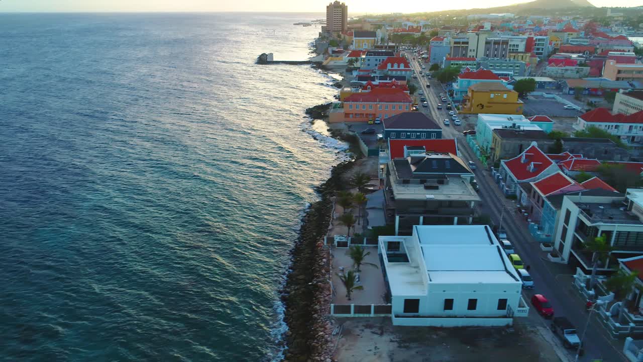 Ripresa aerea 4K con dolly e tilt up che rivela la città di Willemstad e il distretto di Pietermaai a Curaçao, durante il tramonto dell'ora d'oro