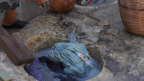 close-up of a woman using a traditional stone trough to wash clothing like in the 1900s during a historical re-enactment in kritou terra, greece