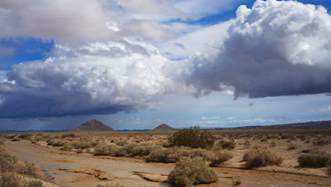 Ein-Unerwarteter-Regenguss-In-Der-Mojave-Wüste-Führt-Zu-Sturzfluten-Und-Erosion,-Da-Trockene-Flussbetten-Mit-Schlammigem-Wasser-Fließen-–-Zeitraffer