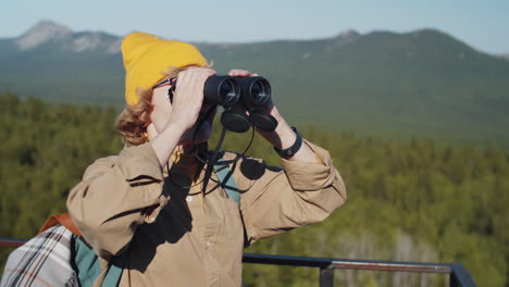 senior woman hiking in the mountains with binoculars