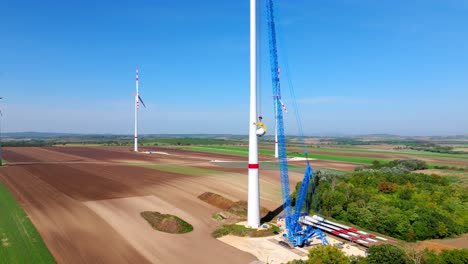 construction of a wind turbine with large crane in summer - drone shot