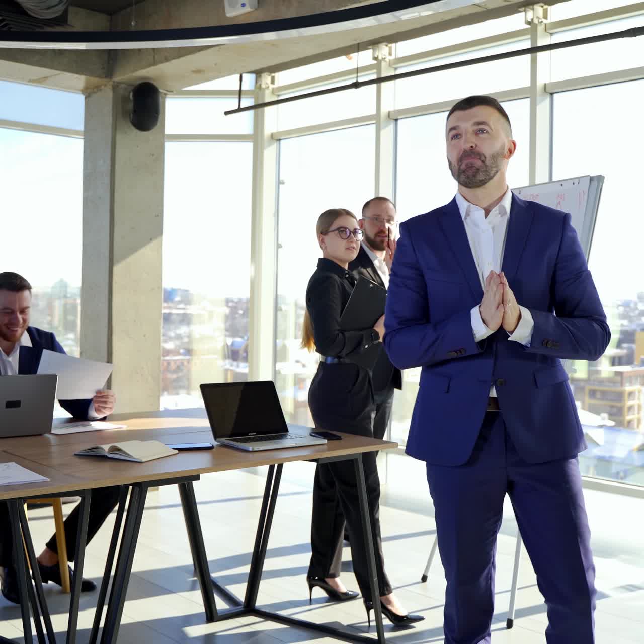 Portrait of businessman in suit in busy office. Successful man in elegant suit speaking about his work on the background of young office workers indoors