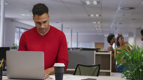 Biracial-businessman-using-laptop-over-business-colleagues-in-office