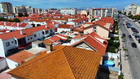 Drohnenaufnahme,-Die-über-Die-Dächer-Von-Stadthäusern-In-Costa-Da-Caparica-Aufsteigt-Und-Sich-Nach-Unten-Neigt