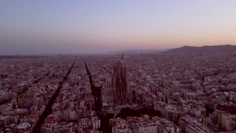 a sundown aerial drone shots of la sagrada familia and barcelona skyline and the sun setting in the background