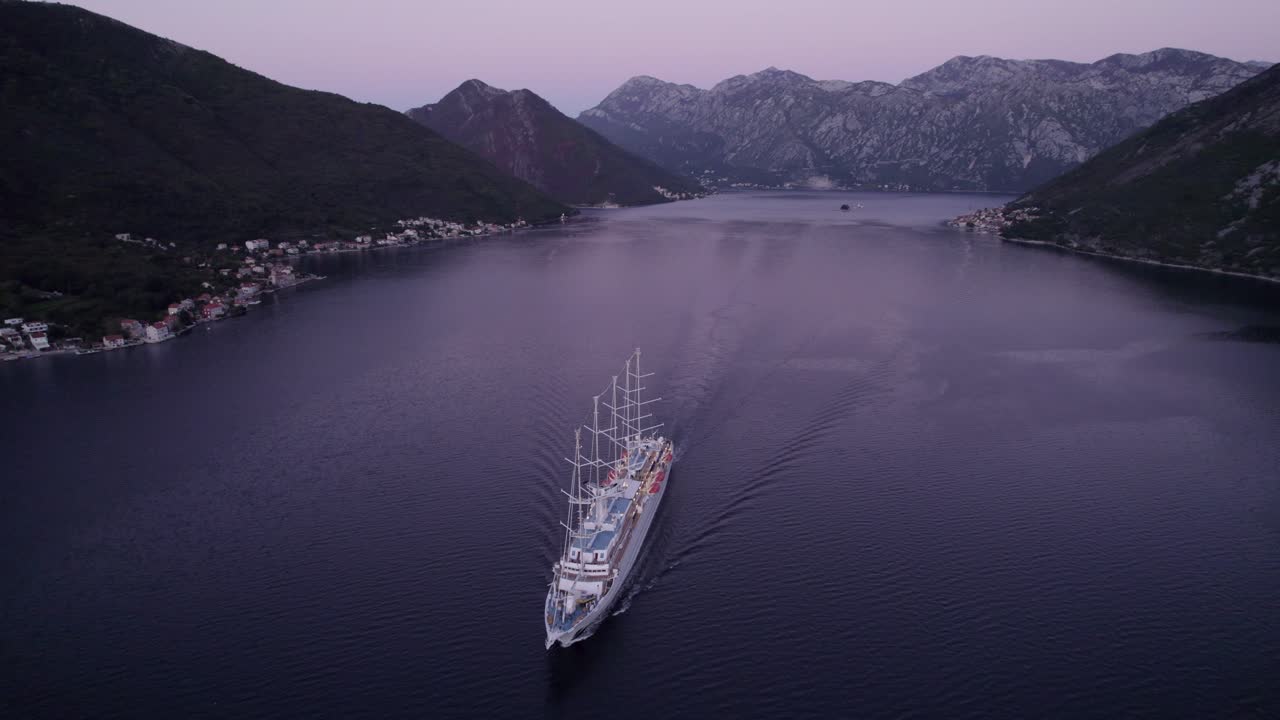 Karadağ, Kotor'da gün doğumu sırasında Kotor Körfezi'ndeki kruvaziyer gemisinin havadan görünümü, büyüleyici gün doğumu ışığı, sakin atmosfer ve huzurlu anları yakalayan yüksek kaliteli drone çekimiyle.