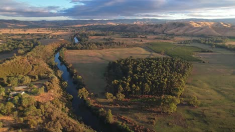 Antena-De-Una-Granja-Cerca-Del-Río-Goulburn-Con-Colinas-Iluminadas-Por-La-Mañana-En-El-Fondo-Cerca-De-Thornton,-Victoria,-Australia