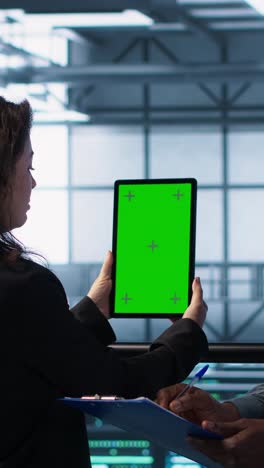 vertical video technicians in data center using green screen tablet, reviewing hardware