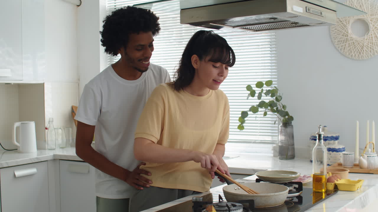 Young Man Kissing Girlfriend when Preparing Breakfast on Sunday Morning