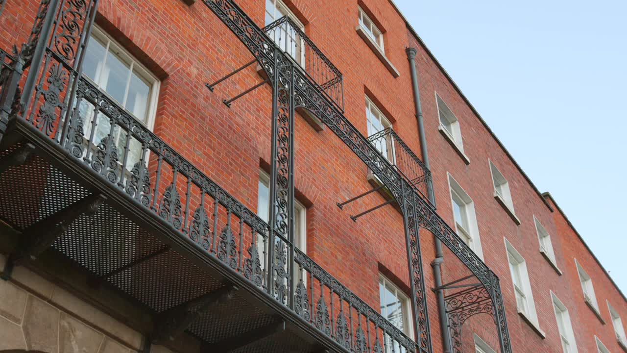 Red brick Georgian building with ornate black ironwork in Dublin, sunny day