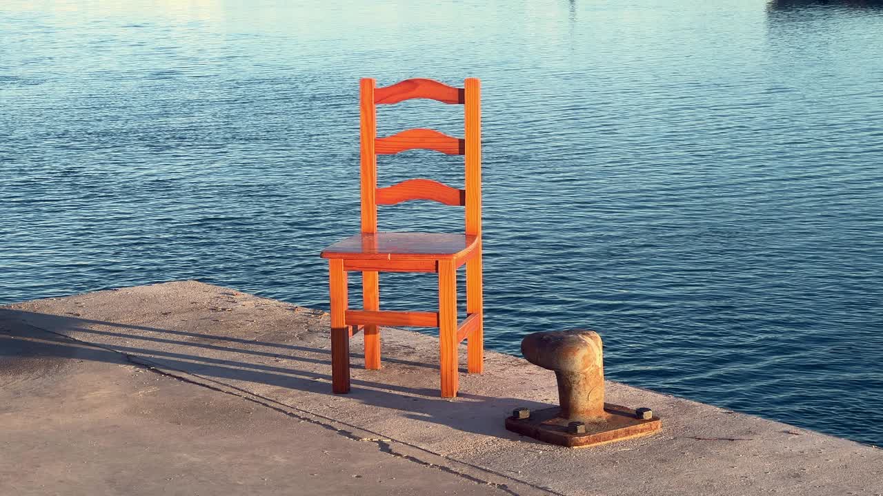 A solitary chair on the pier, no people present, just the sea and a beautiful sunny day